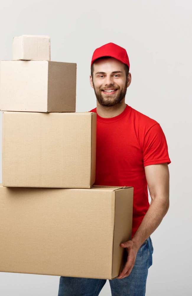 Delivery Concept: Handsome delivery man hold pile cardboard boxes on grey background